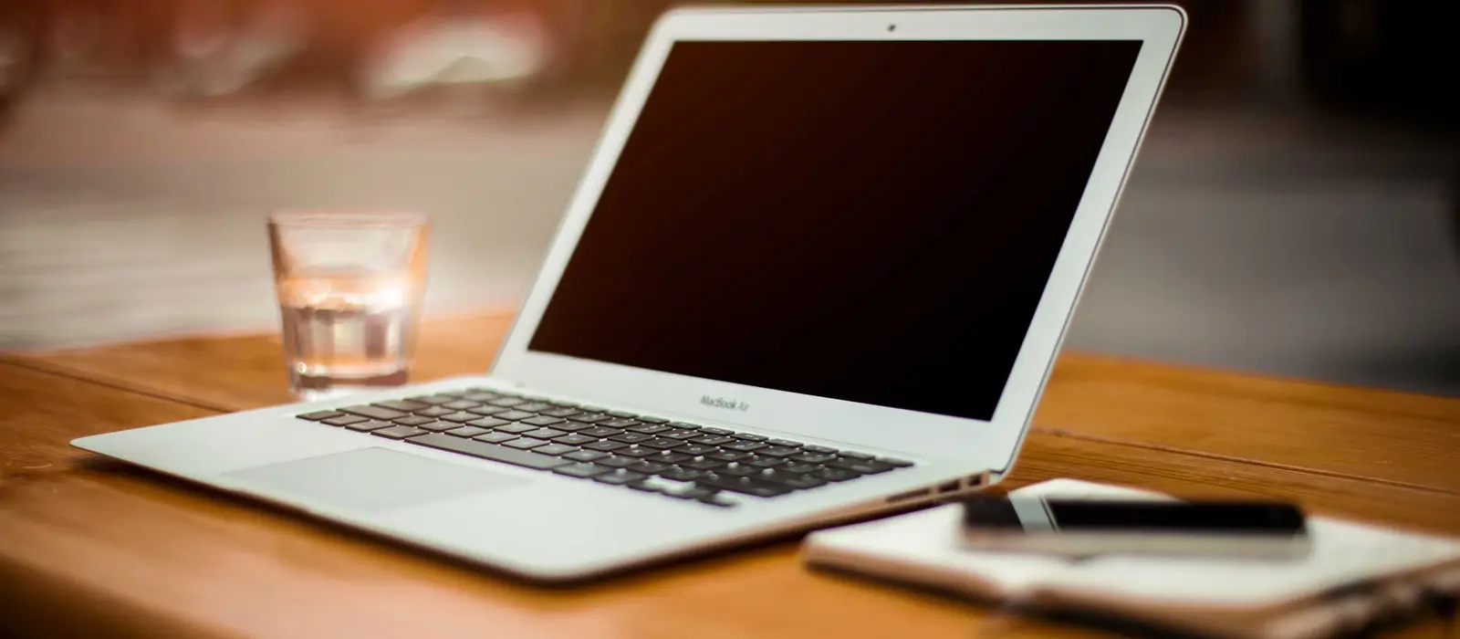 A laptop and a notebook on a wooden desk